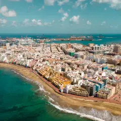 Vista aérea de Las Palmas de Gran Canaria, con la playa, el mar turquesa y el puerto al fondo. Descubre qué ver en Las Palmas de Gran Canaria.