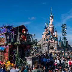 Desfile de **Disneyland Paris Halloween** con Mickey Mouse en un carro espeluznante frente al castillo.