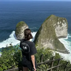 Una mujer admira el paisaje de acantilados verdes y mar turquesa, un momento de su viaje a Indonesia de 15 días.