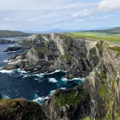 Impresionantes acantilados y el océano Atlántico azul profundo, parte de una ruta por Irlanda. Senderos serpentean por la cima verde.