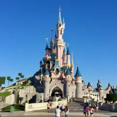 El castillo de la Bella Durmiente se alza majestuoso bajo un cielo azul, invitando a la fantasía.