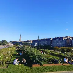 Gente relajándose en un jardín urbano con vistas a Burdeos. ¡Así se llega a la tranquilidad!