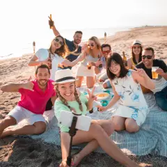 Un grupo de amigos celebra en la playa, un lugar perfecto para disfrutar del sol y la compañía.
