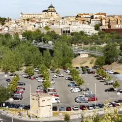 Amplio aparcamiento con muchos coches, ideal para saber donde aparcar en Toledo. Al fondo, la histórica ciudad se alza majestuosa.