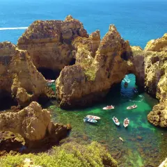 ¡Qué ganas de ir al Algarve en coche! Aquí, barcos exploran cuevas y arcos naturales en aguas cristalinas.