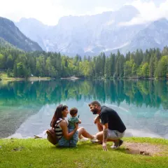 Familia disfrutando del lago turquesa y montañas, un lugar idílico que ver en Eslovenia.