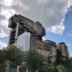La imponente Hollywood Tower Hotel de Disneyland Paris, con andamios y cubiertas, se alza bajo un cielo nublado.