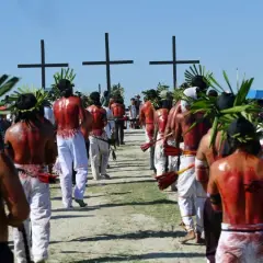 Hombres con coronas de hojas y espaldas ensangrentadas caminan hacia cruces negras, parte de una procesión de **Semana Santa Filipinas**.
