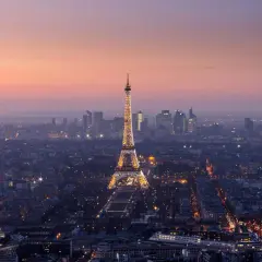 Vista panorámica de París al anochecer, con la Torre Eiffel iluminada y el horizonte de la ciudad. Un recuerdo inolvidable de las visitas a la Torre Eiffel.