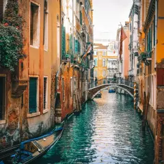 Un canal veneciano con góndola y un puente. El viaje de Milán a Venecia es un sueño hecho realidad.