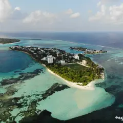 Isla con edificios, campo de fútbol y palmeras, rodeada de aguas turquesas y azules. Un sueño para viajar a Maldivas.