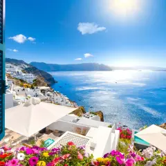 Vista de Santorini, Grecia, con casas blancas en la ladera y el mar azul brillante. ¡Un lugar perfecto donde viajar en junio!
