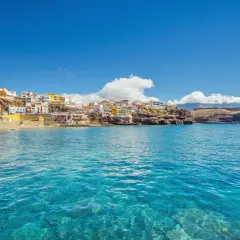 Pueblo costero de casas coloridas en una ladera rocosa, con aguas cristalinas. ¡Un destino ideal donde viajar en febrero barato!
