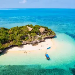 Isla tropical con cabañas y playa de arena blanca, aguas turquesas. La mejor época para viajar a Zanzíbar es ahora.