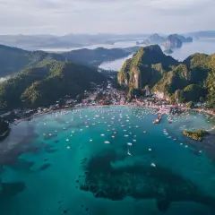 Vista aérea de El Nido, Filipinas. Un mar turquesa lleno de barcos, con una costa verde y montañosa. ¡Perfecto para tu próxima aventura con una tarjeta SIM Filipinas!