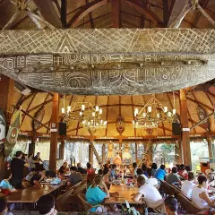 Comedor temático con decoración polinesia, similar a Bora Bora, en PortAventura. Gente disfrutando de un espectáculo.