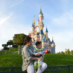 Madre e hijo disfrutan de un día mágico en Disneyland París. El niño, vestido de Buzz Lightyear, sostiene un juguete mientras admiran el castillo.