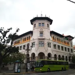 Autobús verde de ALSA en la calle, frente a un edificio histórico. Un buen lugar para aparcar en Santander y disfrutar de la arquitectura.