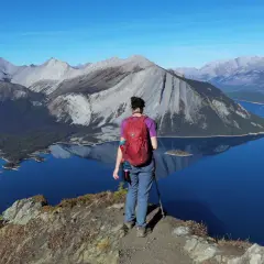 Senderista admira el paisaje montañoso y lagos turquesas, un ejemplo de qué ver en Canadá.