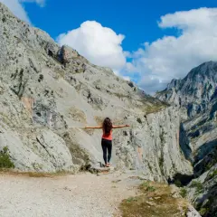 Mujer con brazos extendidos en un desfiladero rocoso, disfrutando de la vista. ¡Una aventura de Cantabria en 4 días!