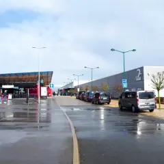 Llegando a **París Beauvais al centro**, taxis esperan bajo un cielo nublado. El aeropuerto tiene una zona de embarque y un edificio largo con el número 2.