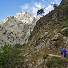 Dos niños caminan por un sendero rocoso en un desfiladero, una ruta para llegar a Bulnes.