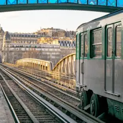 Un tren del metro de París cruza un puente al atardecer. El horario del metro de París es fácil de consultar para planificar tu viaje.