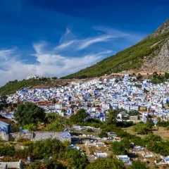 Vista panorámica de Chefchaouen, la ciudad azul, encaramada en una ladera montañosa. A pesar de su belleza, se rumorea que Chefchaouen es peligroso, con un cementerio en primer plano.