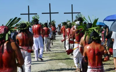 Hombres con coronas de hojas y espaldas ensangrentadas caminan hacia cruces negras, parte de una procesión de **Semana Santa Filipinas**.