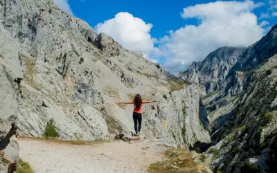 Mujer con brazos extendidos en un desfiladero rocoso, disfrutando de la vista. ¡Una aventura de Cantabria en 4 días!
