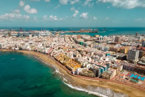 Vista aérea de Las Palmas de Gran Canaria, con la playa, el mar turquesa y el puerto al fondo. Descubre qué ver en Las Palmas de Gran Canaria.