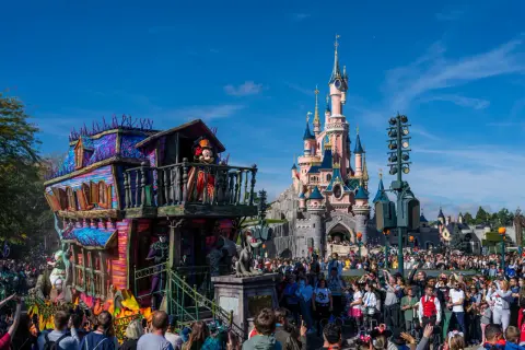 Desfile de **Disneyland Paris Halloween** con Mickey Mouse en un carro espeluznante frente al castillo.