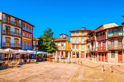 Plaza con edificios coloridos y terrazas. Un lugar perfecto donde viajar en marzo Europa para disfrutar del sol y la arquitectura.