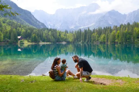 Familia disfrutando del lago turquesa y montañas, un lugar idílico que ver en Eslovenia.