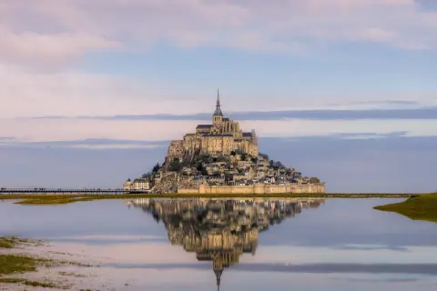 Mont Saint-Michel como llegar: la abadía reflejada en el agua, un sueño al amanecer.