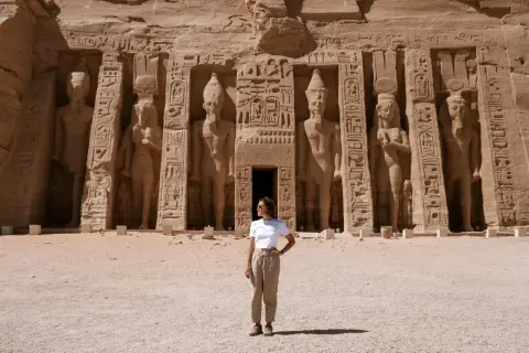 Mujer posa frente a colosales estatuas en Abu Simbel. ¡Excelentes consejos para viajar a Egipto!