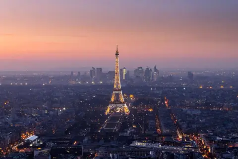 Vista panorámica de París al anochecer, con la Torre Eiffel iluminada y el horizonte de la ciudad. Un recuerdo inolvidable de las visitas a la Torre Eiffel.