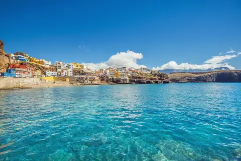 Pueblo costero de casas coloridas en una ladera rocosa, con aguas cristalinas. ¡Un destino ideal donde viajar en febrero barato!