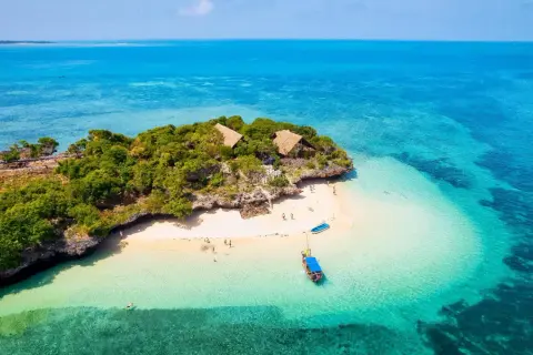 Isla tropical con cabañas y playa de arena blanca, aguas turquesas. La mejor época para viajar a Zanzíbar es ahora.
