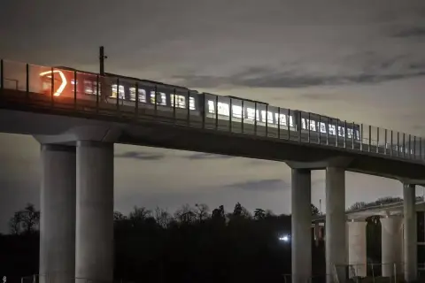 Un tren ilumina la noche sobre un viaducto, parte de las **líneas metro París**. Sus luces brillan a través de las ventanas, creando un espectáculo nocturno.