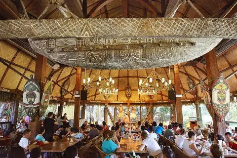 Comedor temático con decoración polinesia, similar a Bora Bora, en PortAventura. Gente disfrutando de un espectáculo.
