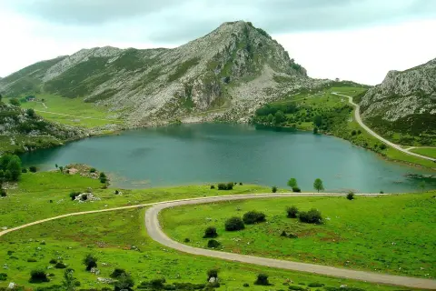 Lago en Cangas de Onís que ver: un paisaje montañoso verde con un lago sereno y carreteras serpenteantes.