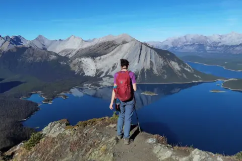 Senderista admira el paisaje montañoso y lagos turquesas, un ejemplo de qué ver en Canadá.
