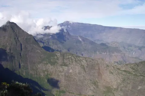 Impresionantes montañas en la isla Reunión, con nubes que envuelven picos escarpados, sugiriendo los peligros de su terreno.