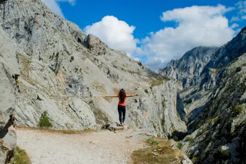 Mujer con brazos extendidos en un desfiladero rocoso, disfrutando de la vista. ¡Una aventura de Cantabria en 4 días!