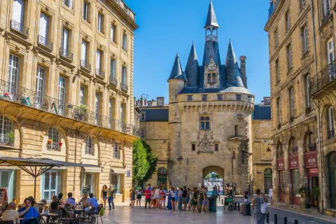 Plaza con la Giralda de Burdeos y edificios históricos. Gente paseando y disfrutando de terrazas. Merece la pena visitar Burdeos.