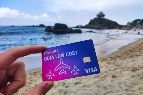 Tarjeta Revolut "Guía Low Cost" en una playa paradisíaca. Descubre cómo funciona Revolut en el extranjero sin comisiones ocultas.