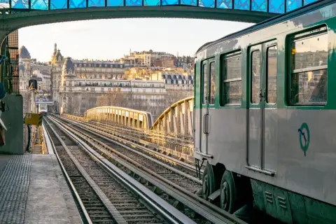 Un tren del metro de París cruza un puente al atardecer. El horario del metro de París es fácil de consultar para planificar tu viaje.