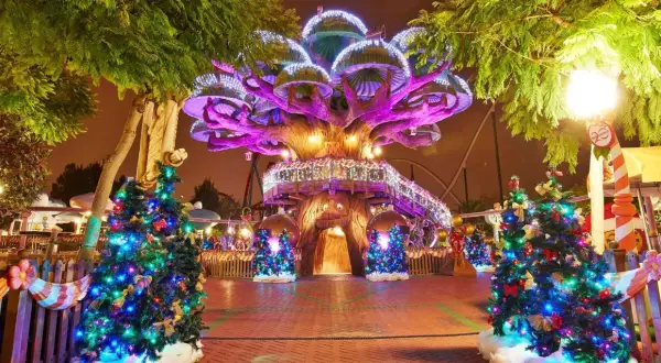 Árboles de Navidad iluminados y decorados en PortAventura en Navidad, con un árbol central gigante y luces festivas.