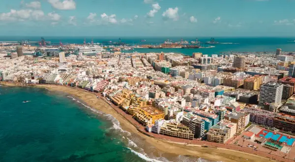 Vista aérea de Las Palmas de Gran Canaria, con la playa, el mar turquesa y el puerto al fondo. Descubre qué ver en Las Palmas de Gran Canaria.